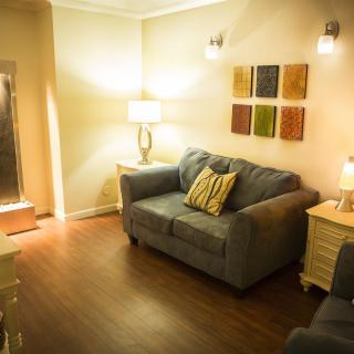 A cozy living room with a comfortable sofa, decorative pillows, warm lighting, and colorful wall art.