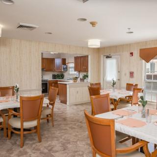 A cozy dining area with wooden tables and chairs, adjacent to a kitchen.