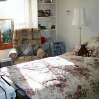 A cozy bedroom with floral bedding and sunlight streaming through the window.