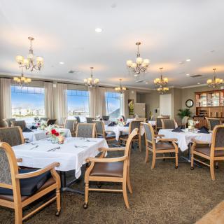 An elegant dining room with neatly arranged tables and chairs, adorned with chandeliers.