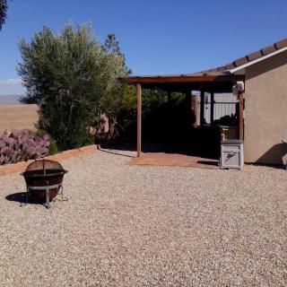 A serene backyard with a gravel landscape, featuring a fire pit and covered patio area.