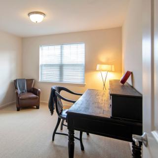 A cozy home office with a desk and chair, illuminated by a lamp next to a window.
