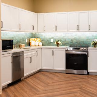 A modern kitchen featuring white cabinets, sleek appliances, and a stylish green backsplash.