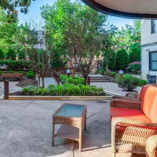 A serene outdoor patio area featuring comfortable seating and lush garden surroundings.