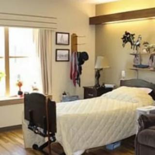 A cozy hospital room with a bed, window, and various decorations.