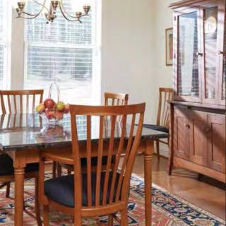 A cozy dining room with a wooden table and chairs, a glass cabinet, and natural light streaming through the windows.