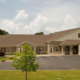A suburban building with a stone facade and a manicured lawn under a cloudy sky.