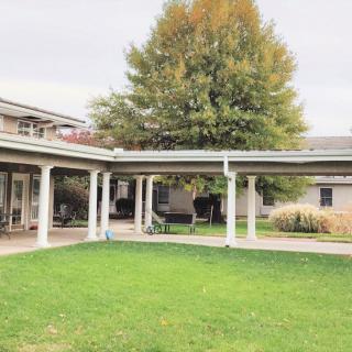 A scenic view of a courtyard with a covered walkway and lush green lawn.
