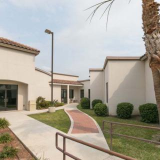 A modern building exterior with a landscaped pathway and greenery.