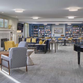 A modern lounge with comfortable seating, bookshelves, and bright lighting.