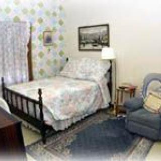 A cozy bedroom with a bed, armchair, and decorative elements.