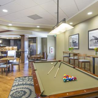 A stylish game room featuring a billiard table with cues, surrounded by comfortable seating and modern decor.
