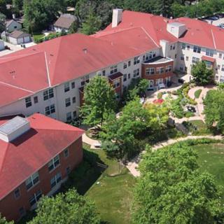 Aerial view of a red-roofed building surrounded by trees and gardens.