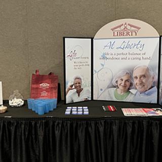 A promotional booth for a senior living community featuring informational materials and branding.