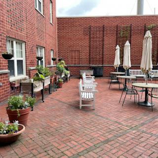 A cozy outdoor patio space with brick flooring, seating arrangements, and potted plants.