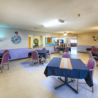 An indoor dining area with arranged tables and chairs, featuring decorative elements on the walls.