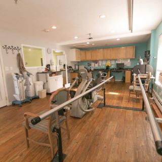 A rehabilitation room equipped with exercise machines and parallel bars for physical therapy sessions.