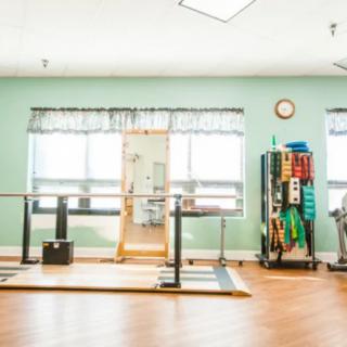 A physical therapy room equipped with various gym tools and parallel bars for rehabilitation exercises.