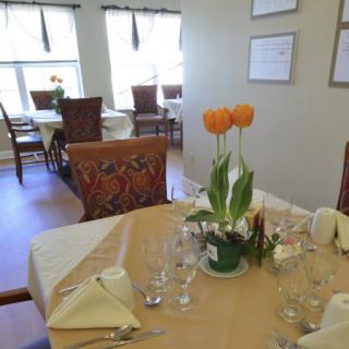 A tastefully set dining table with orange tulips in a cozy restaurant.