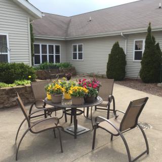 A cozy patio area with a table and chairs surrounded by potted flowers.