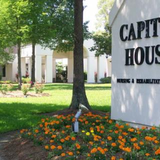 A vibrant view of the Capitol House surrounded by lush greenery and colorful flowers.