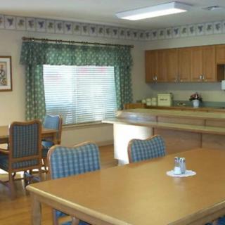 A cozy dining room with a table, chairs, and a kitchen area.