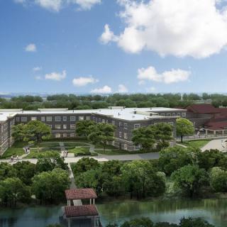 A modern architectural complex surrounded by lush greenery and a serene garden, under a bright blue sky.