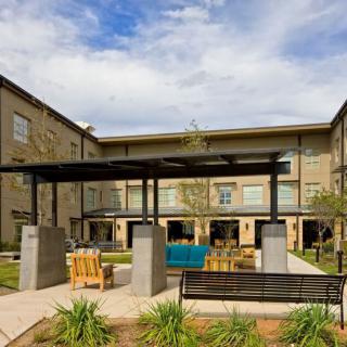 A modern apartment complex featuring an inviting courtyard with outdoor seating and a pergola.