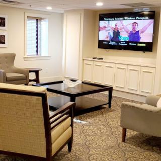 A cozy living room with comfortable seating and a large television on the wall.