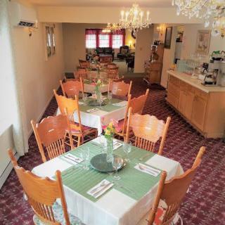 A cozy dining area with neatly arranged tables and chairs, adorned with chandeliers.
