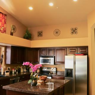 A modern kitchen interior with stainless steel appliances, decorative elements, and a flower arrangement on the countertop.