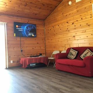 A cozy living room with wooden paneling and a red sofa.