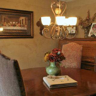 A cozy dining room featuring a chandelier, a wooden table with a vase of flowers, and elegant decor.