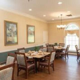 A well-decorated dining room with several tables and chairs, featuring elegant lighting and artwork on the walls.