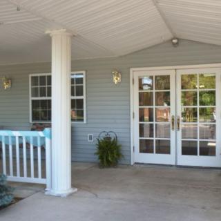 A residential porch with double glass doors and a covered patio area.