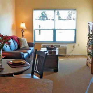 A cozy living room with a sofa, lamp, and table near a large window.