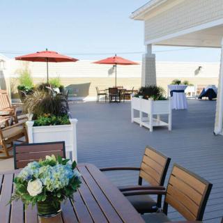 A scenic beachfront patio with wooden furniture and red umbrellas, perfect for relaxation.
