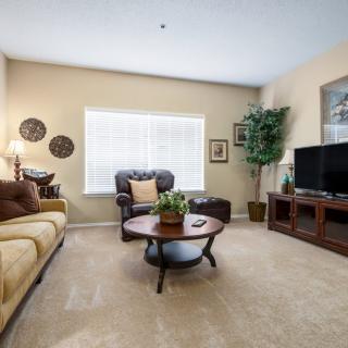 A cozy living room featuring a sofa, coffee table, television, and decorative elements with natural lighting.