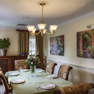 A well-decorated dining room with a set table, chandelier, and wall art.