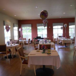 A decorated dining room with tables set and balloons for a special event.