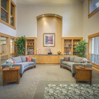 A welcoming lobby area with comfortable seating, decorative plants, and bookshelves.