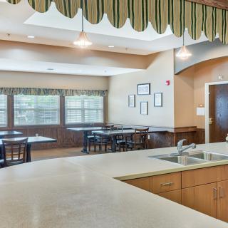A spacious kitchen with a dining area featuring tables, chairs, and large windows.