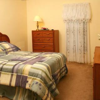 A cozy bedroom with a bed, dresser, and a lamp.