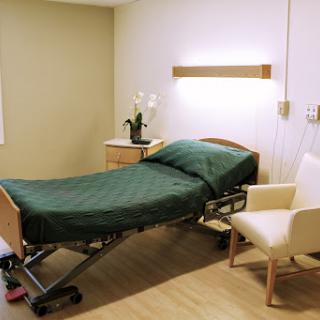 A well-equipped patient room featuring an adjustable hospital bed and a comfortable chair.