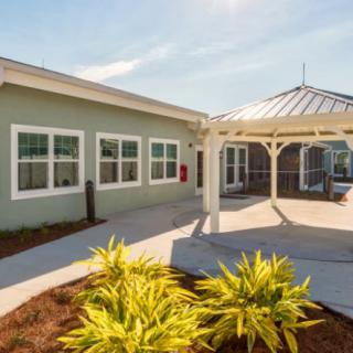 A modern building exterior with a gazebo and well-maintained landscaping on a sunny day.