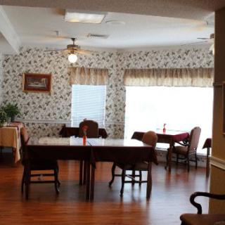 A cozy dining room with elegant wallpaper and large windows.