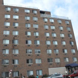 A multi-story brick apartment building with numerous windows in an urban setting.