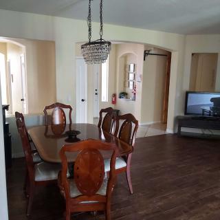 A cozy dining room with a wooden table and chairs, complemented by a chandelier and wood flooring.