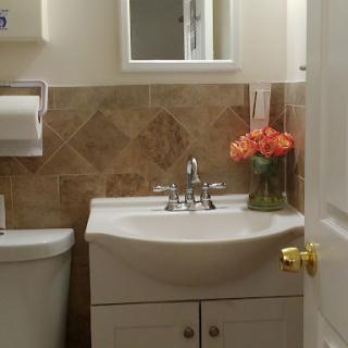 A cozy and well-decorated bathroom featuring a sink, toilet, and a vase of flowers.