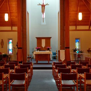 A serene view of a church interior featuring an altar and rows of benches.